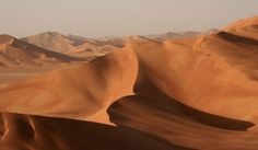 sand dunes in the desert with mountains in the background