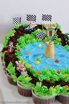 cupcakes with green frosting and race cars around them on a white plate