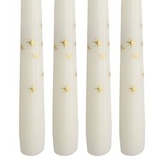 four white candles with gold stars on them are lined up against a white background,