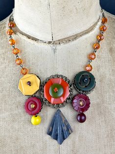 This is a LIMITED EDITION of a collection of Bakelite buttons in a statement bib necklace. A very Fall color palette runs throughout accented with tangerine, sunflower & burgundy Swarovski crystals. The brass element at bottom is antiqued with a little speckling celebrating the transition of the Fall colors. An eye-catching piece that will get you lots of attention! Wears best with a v-neck or scoop neck. Wear with an open flannel shirt or a dress! This is packed in a gift box and ready to ship. Artisan Orange Necklaces For Crafting, Unique Multicolor Jewelry With Bead Caps, Unique Necklaces With Bead Caps For Gifts, Adjustable Upcycled Necklace For Gift, Unique Upcycled Jewelry Gift, Unique Upcycled Jewelry For Gifts, Unique Upcycled Jewelry As A Gift, Jewelry Collage, Bakelite Buttons