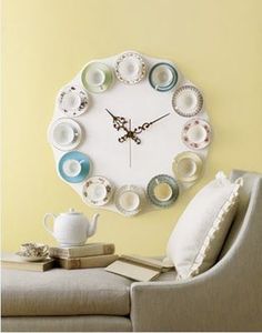 a clock that is on the side of a wall with cups and saucers around it