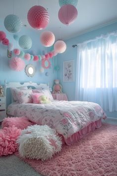 a bedroom decorated in pink and blue with pom poms hanging from the ceiling