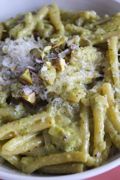 a white bowl filled with pasta covered in pesto sauce