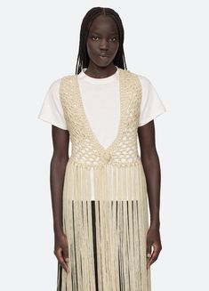 The Simonne macramé vest features fringe detailing. Details: 100% polyester button front closure designed for a relaxed fit style #PF24-190 model is 5'10'' and wearing a size S/M PRE-ORDER: EXPECTED DELIVERY 6/15-7/15 Beige Sleeveless Fringe Top, Spring Sleeveless Vest With Tassels, Fitted Fringe Vest, Sleeveless Tassel Vest For Spring, Spring Sleeveless Top With Beaded Fringe, Sleeveless Outerwear For Summer Festivals, Summer Festival Sleeveless Outerwear, Sleeveless Summer Vest With Tassels, Chic Beige Fringe Tops