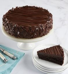 a chocolate cake sitting on top of a white plate next to a knife and fork