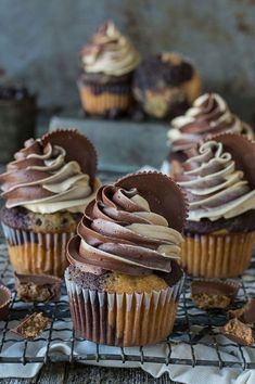 three cupcakes with chocolate frosting on a cooling rack