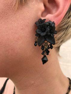 Pretty Floral Black Earrings, hand beaded with glass beads and hand painted resin flowers. A cluster of flowers hugs the earlobes and are finished with jet black beads as a drop. This is a quality piece of jewelry that will last a life time. Created by designer Colleen Toland who has been creating her unique style of vintage jewelry for more than 30 years. Earrings measure .75 inches by 1.25 inch. All metal components are nickel free and are plated in antique gold. All our post earrings are hypo Handmade Black Dangle Clip-on Earrings, Adjustable Black Flower Earrings For Pierced Ears, Adjustable Black Flower Earrings, Handmade Flower Earrings For Party, Hand Painted Black Polymer Clay Jewelry, Handmade Black Drop Flower Earrings, Handmade Black Drop Earrings, Black Hand Painted Drop Earrings, Black Bohemian Polymer Clay Jewelry