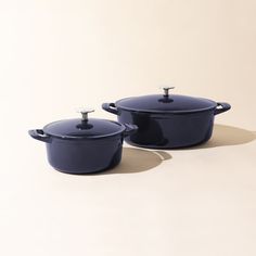 two blue casserole dishes sitting side by side on a white surface, one has a lid and the other has a handle