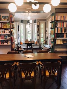 a room filled with lots of furniture and bookshelves next to a table surrounded by chairs