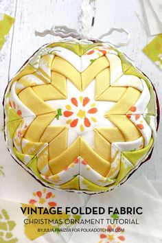 an ornament made out of fabric on top of a white wooden table with yellow flowers