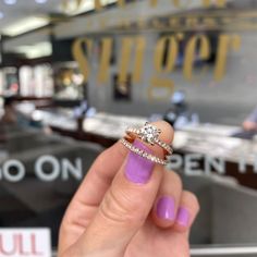 a woman's hand holding a diamond ring in front of a store display window