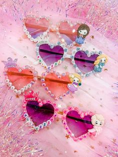 three heart shaped hair clips with little mermaids on them sitting on a pink background