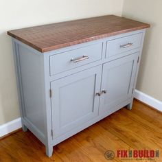 a kitchen island with two drawers and a butcher block top on the bottom, in front of a white wall