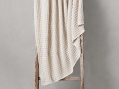 a white blanket sitting on top of a wooden chair