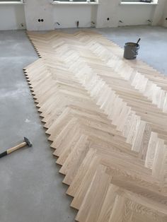 an unfinished wooden floor with a bucket and hammer on the ground in front of it