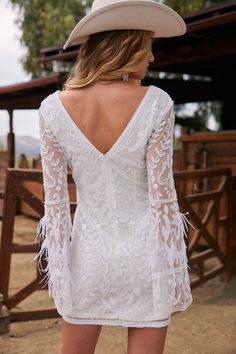 the back of a woman wearing a white dress and cowboy hat