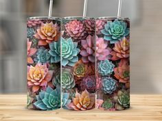 two stainless steel tumblers with colorful succulents printed on them, sitting on a wooden table