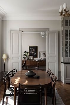 a dining room table with chairs and a vase on top of it in front of a doorway