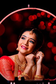 a woman in a red and gold outfit posing for the camera with her hands on her chin