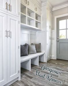 a room with some white cabinets and gray pillows on the bench in front of it