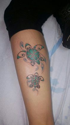 a tattoo on the leg of a woman with a green turtle and swirls design