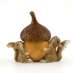 three little mouses are sitting around an acorn shaped figurine on a white background