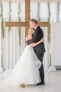 a bride and groom hugging each other in front of a cross