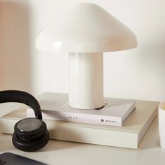 a white lamp sitting on top of a table next to a book and headphones