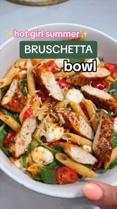 a white bowl filled with pasta and chicken on top of a table next to a hand