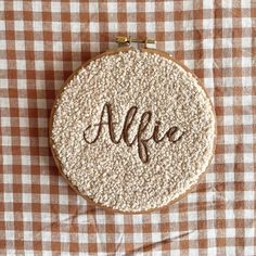 an embroidered monogrammed name on a brown and white checkered tablecloth with the word afie