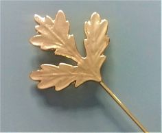 a gold colored leaf shaped brooch on a blue background