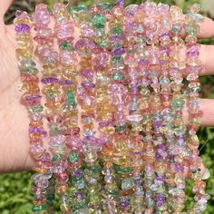 a hand holding several different colored glass beads in it's left hand and the second bead is being held up