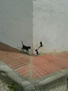 a cat and dog are painted on the side of a building with an arrow in it's mouth