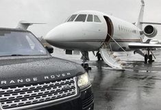 a range rover parked next to an airplane on the tarmac