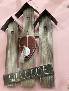 a wooden sign that says welcome with a heart hanging from the front and side of it