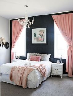 a bedroom decorated in pink and black with a chandelier hanging from the ceiling