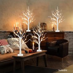 three white lighted trees are sitting on a coffee table