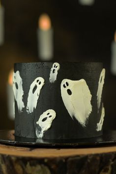 a black cake with white frosting and spooky ghost faces on it's side