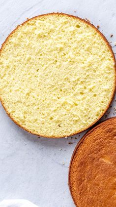 two cakes sitting next to each other on top of a white tablecloth covered surface