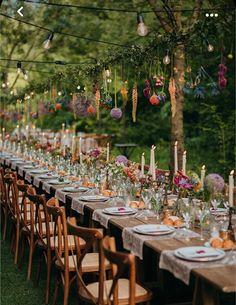 a long table is set with candles, plates and place settings for an outdoor dinner