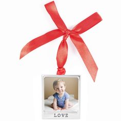 an ornament hanging from a red ribbon on a white background with the word love in it