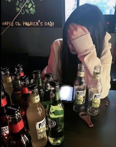 a woman sitting at a table with many beer bottles in front of her and behind her head is a bottle opener