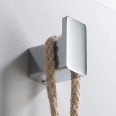 a rope is hanging on the wall next to a light fixture with a square shaped mirror