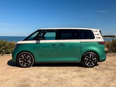 a green and white minivan parked in front of the ocean