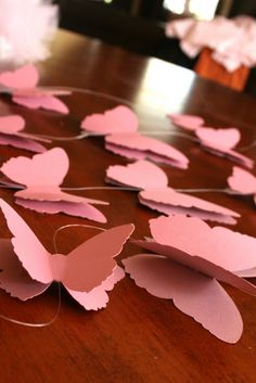 some pink paper butterflies on a wooden table