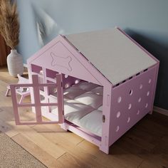 a pink dollhouse bed with white sheets and pillows on the floor next to a vase