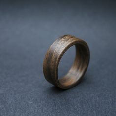 a wooden ring sitting on top of a gray table next to a black wall and floor