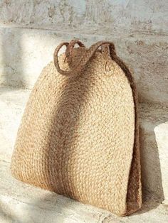 a straw bag sitting on the side of a stone wall next to a cement step