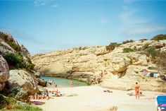 people are on the beach near some rocks