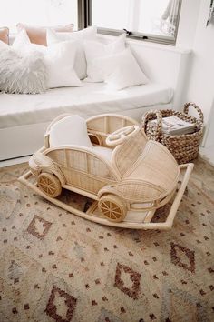 a wicker toy car sitting on top of a rug in front of a white couch